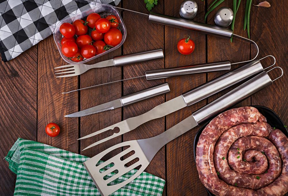 Barbecue tools and sausage on wooden table