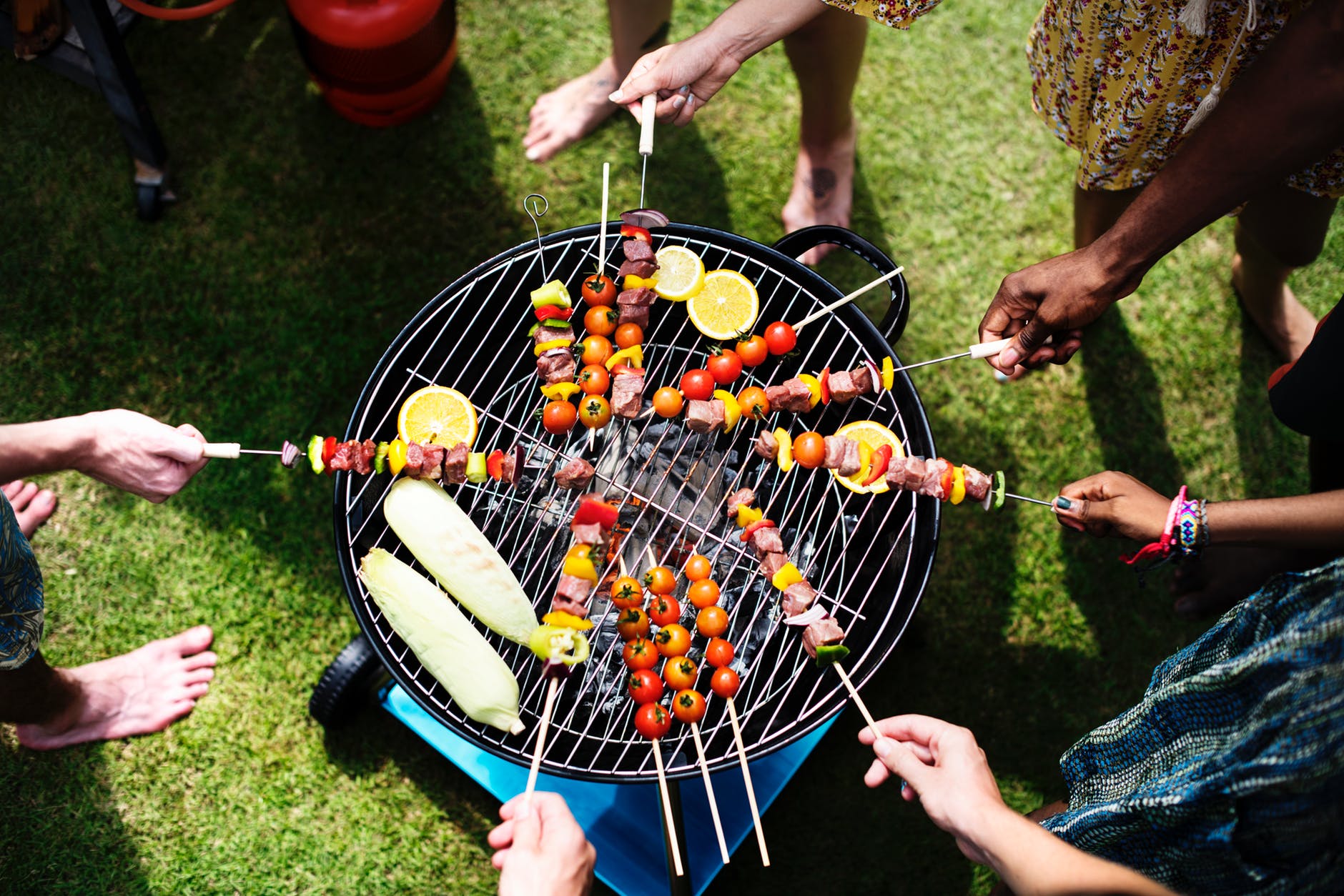 people barbecuing meat on a portable grill