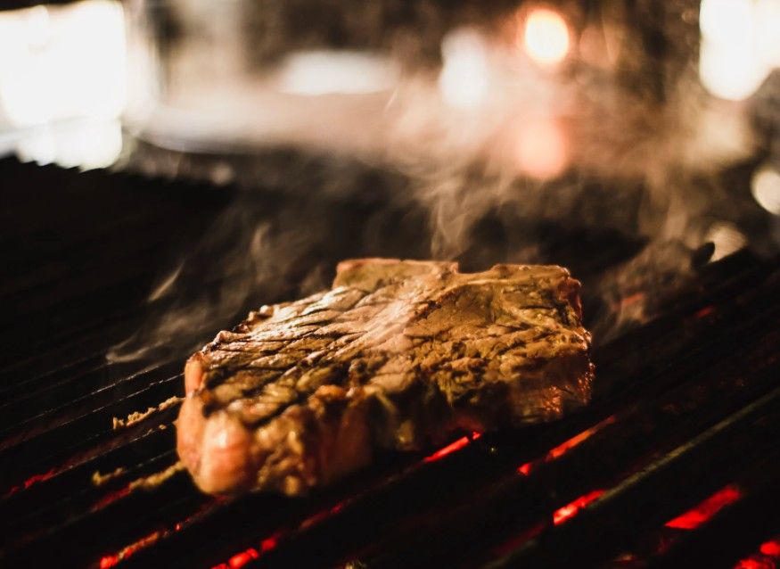 A steak being grilled on top of a grate