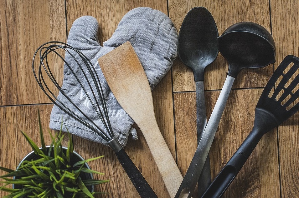 Kitchen utensils, including a glove with a wooden background