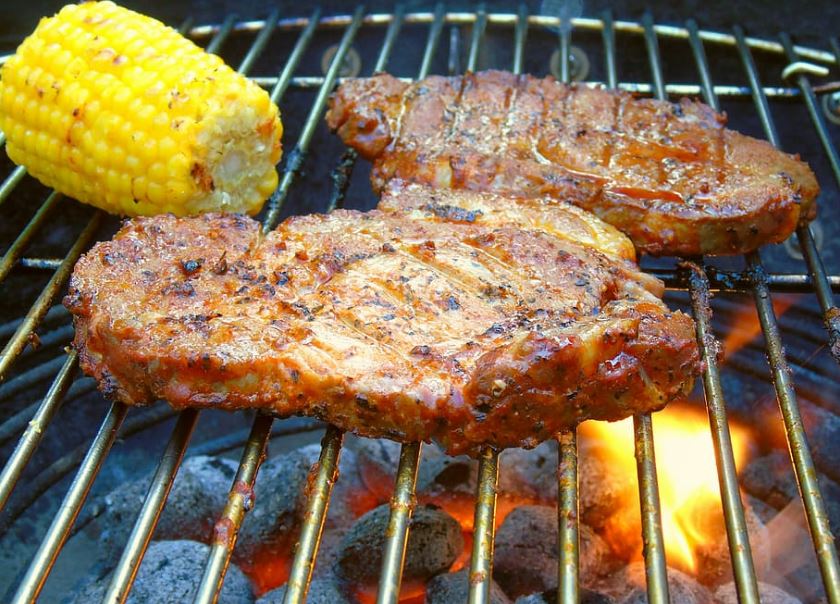 Steak and corn being grilled on a charcoal grill