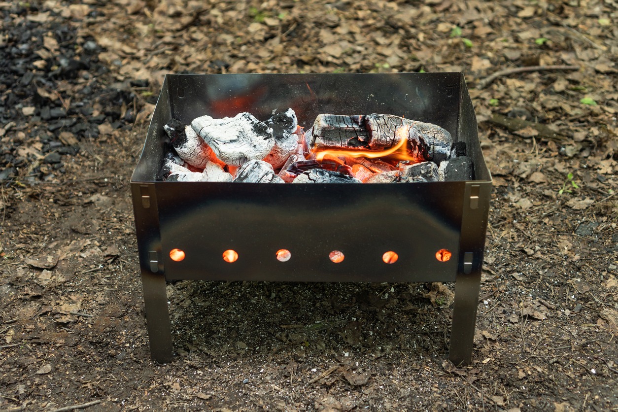 Small lightweight portable barbecue grill for camping with burning coals. Before barbecuing.