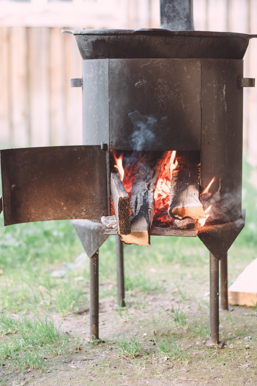Open firebox of yard cauldron, with firewood burning in it